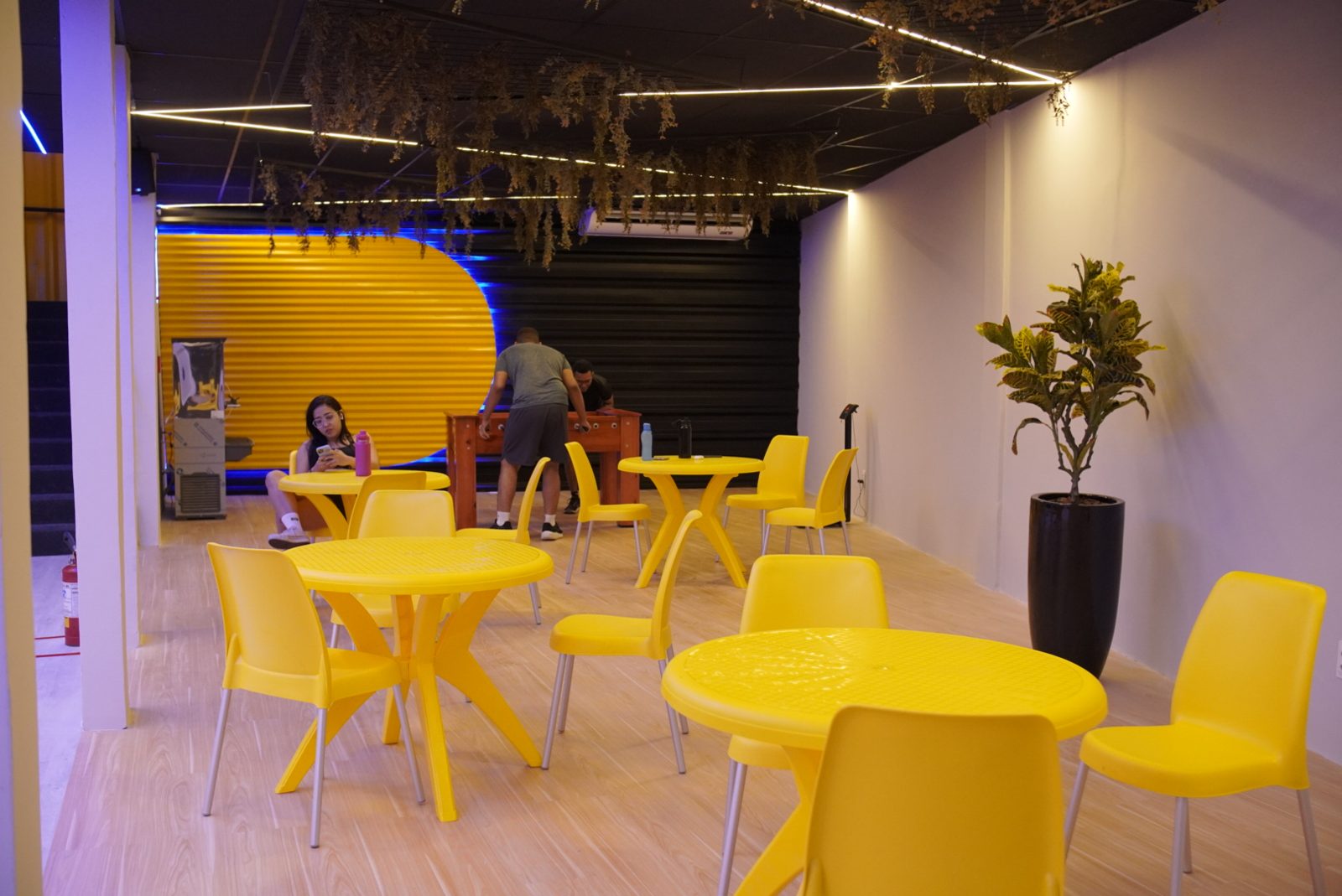 Lounge de convivência com mesas e cadeiras amarelas na unidade Abreu e Lima