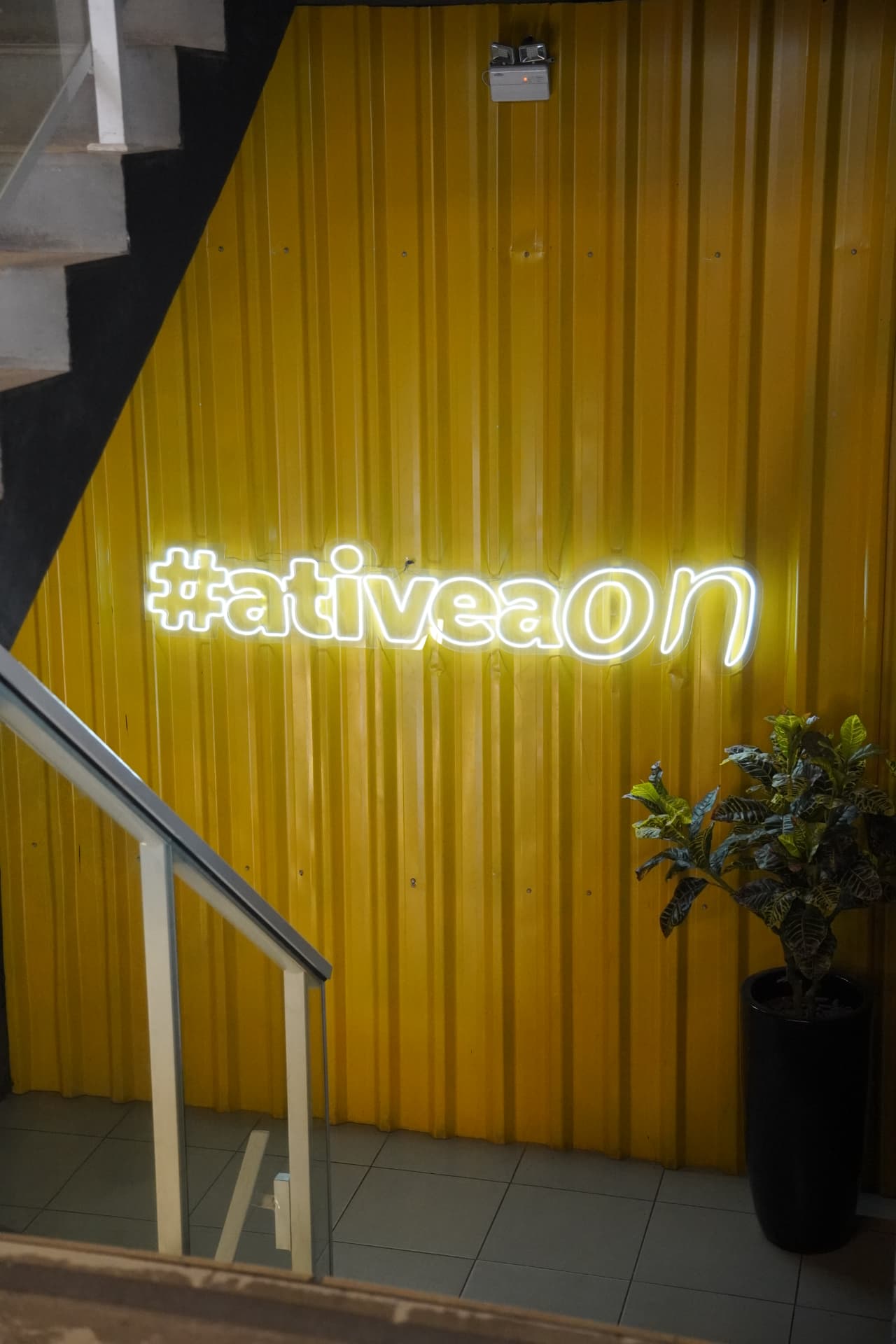 Parede amarela com letreiro neon #ativeaon na unidade Paulista