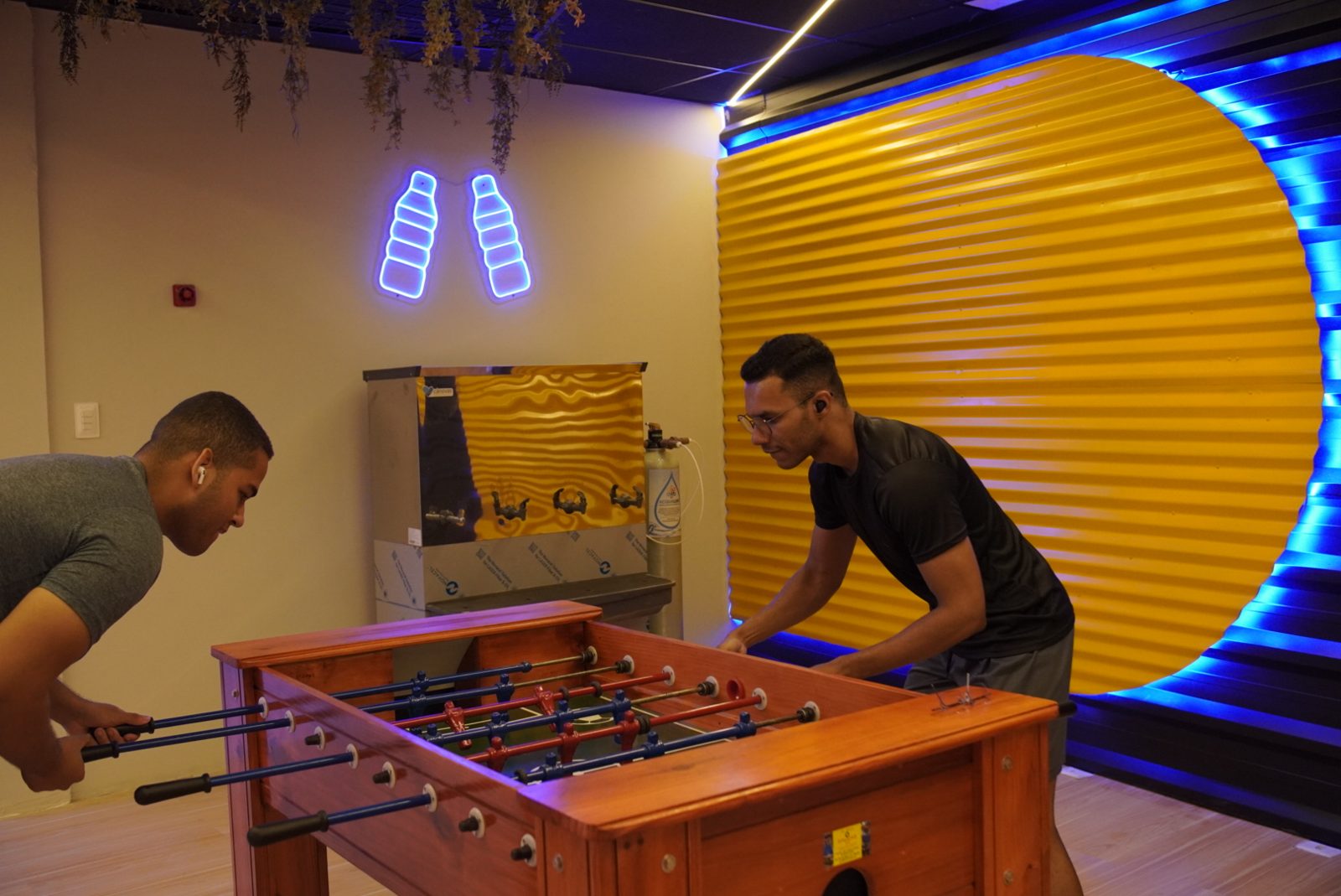 Alunos jogando pebolim na área de descanso com neon da unidade Abreu e Lima