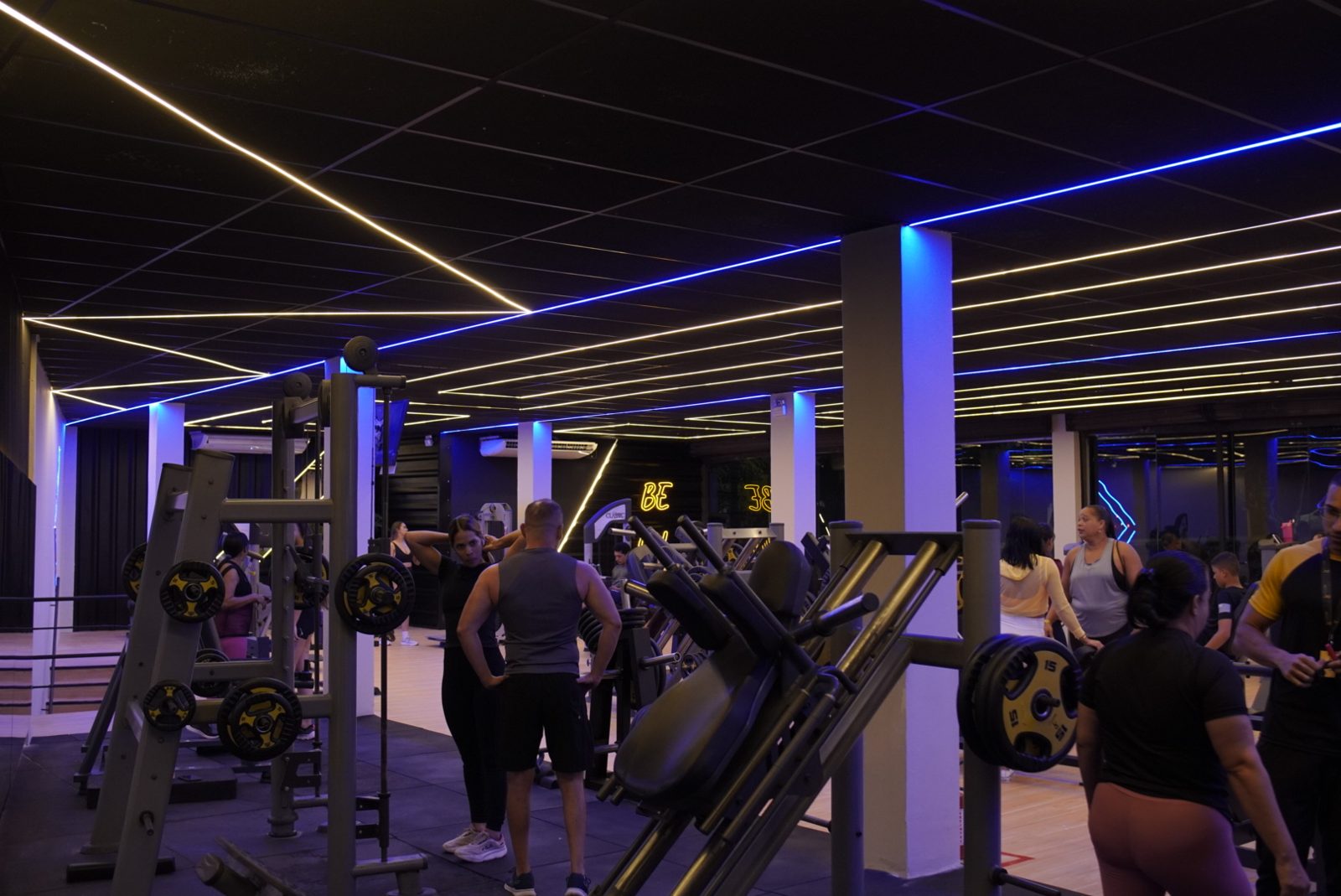Salão de musculação com máquinas, pesos e iluminação em LED azul e amarela na unidade Abreu e Lima